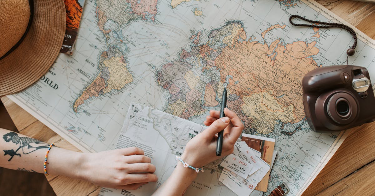 Top view of a woman's hands planning a trip with a map, camera, and travel items.